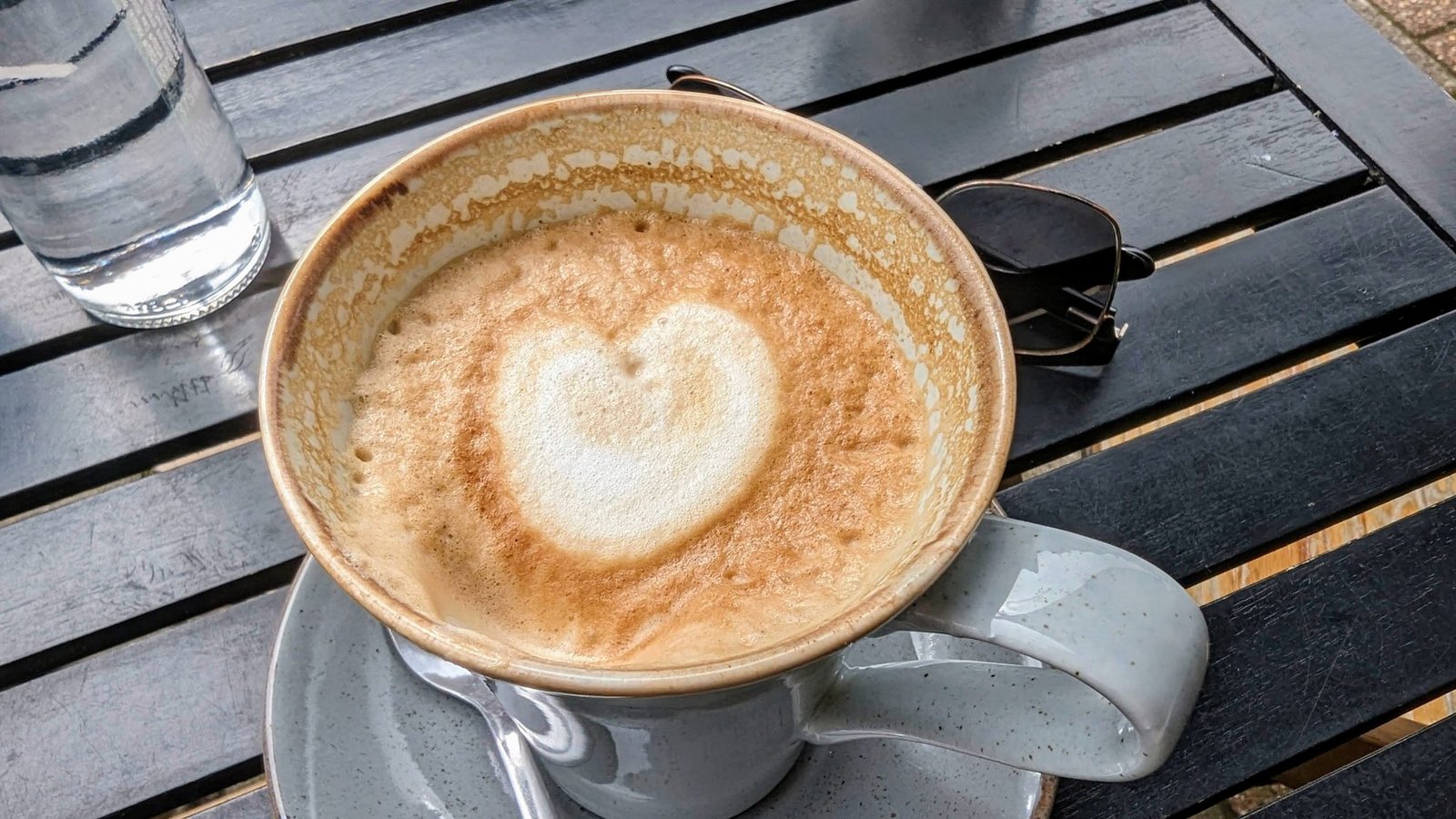 A cappuccino with heart-shaped latte art on a wooden table in Campbeltown.