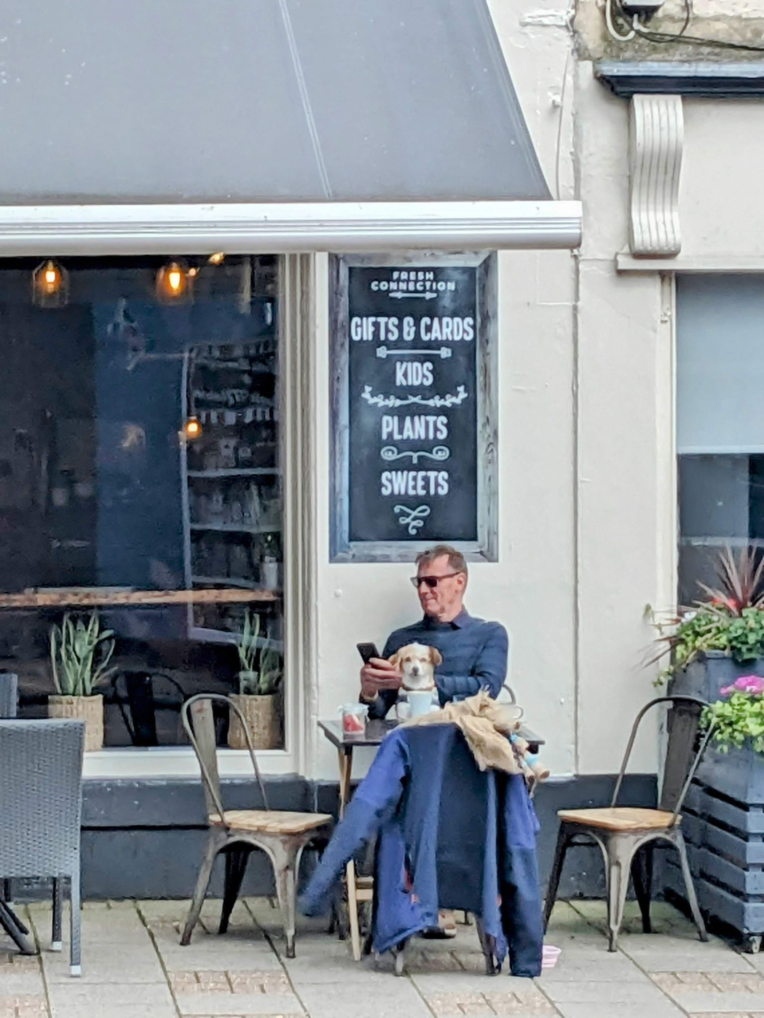 A man and a small dog at an outdoor table outside The Fresh Connection coffee shop in Campbeltown.