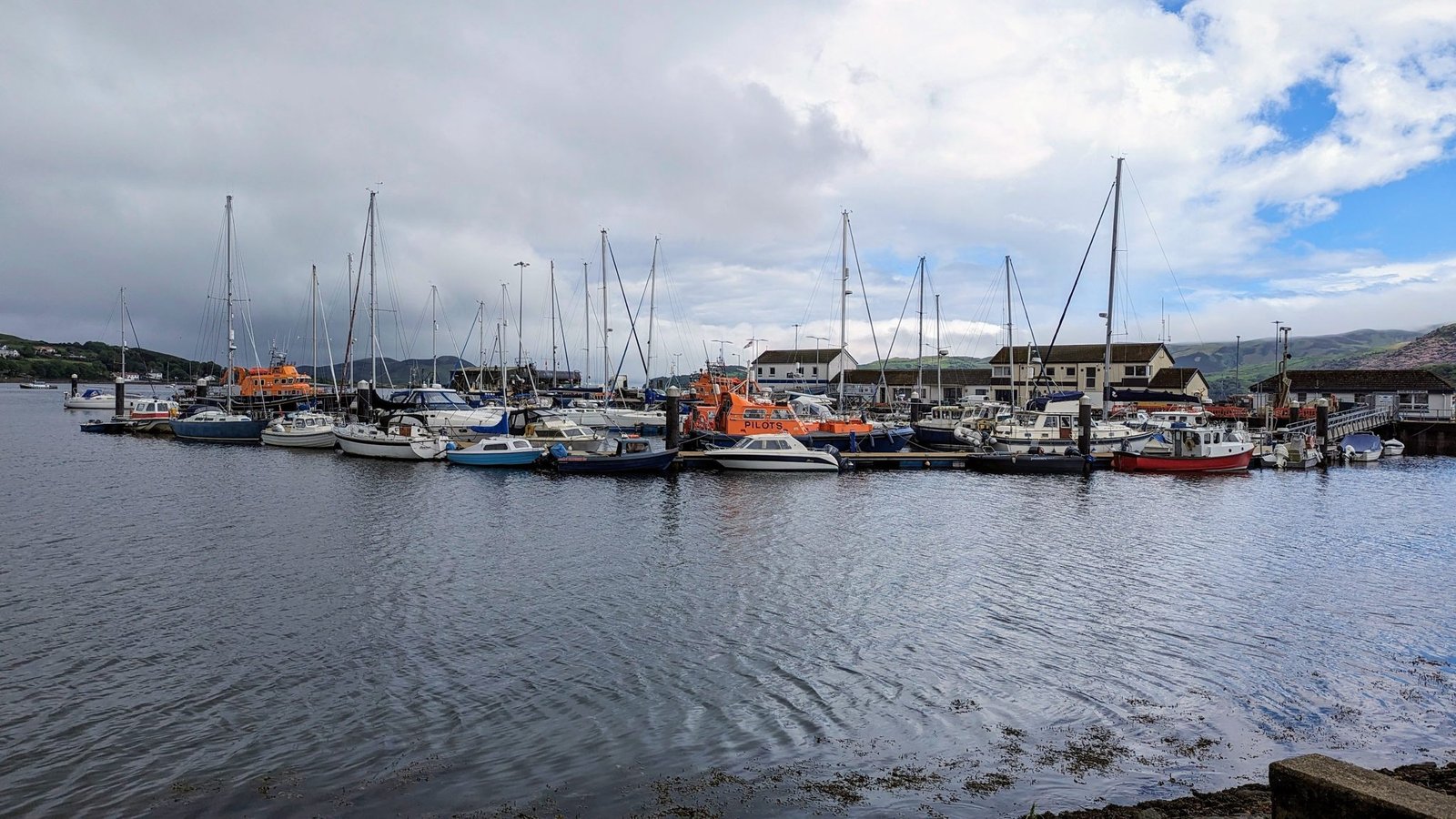 Campbeltown harbour and marina full of yachts and fishing boats, the town and hills behind.