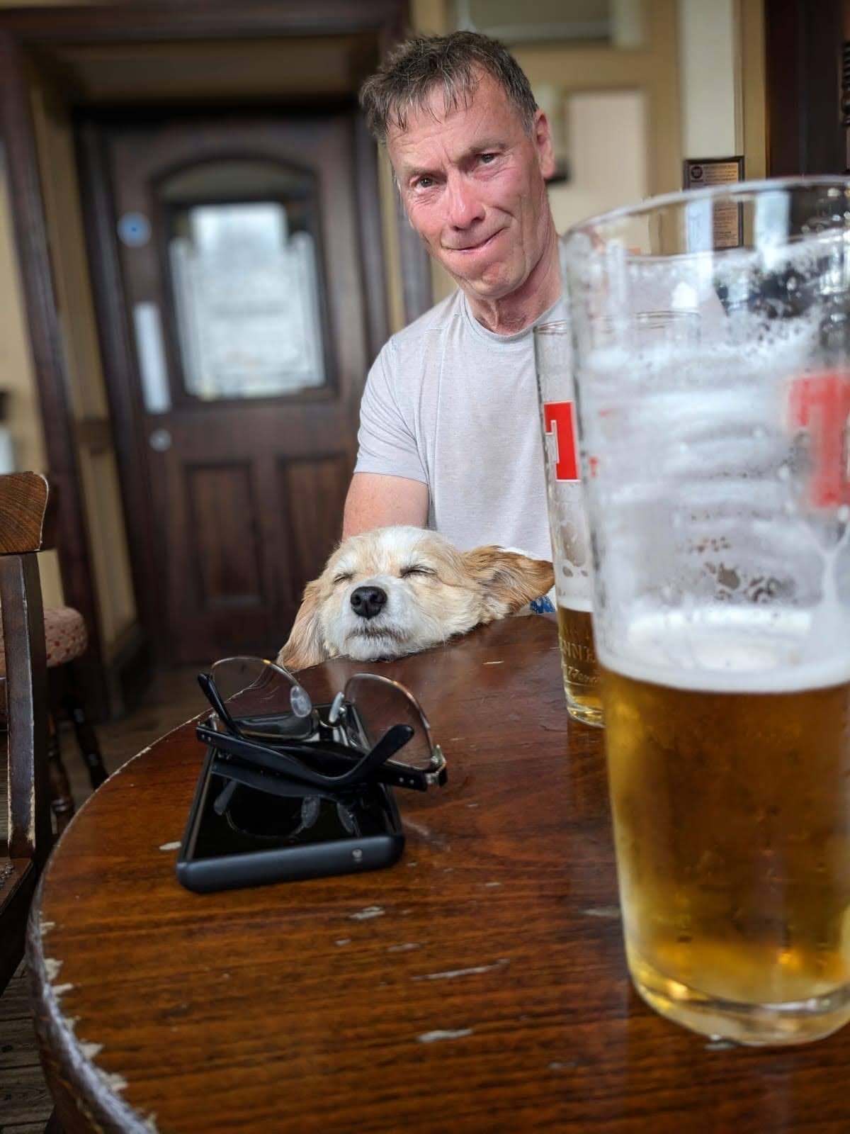 A pint of beer on a table with a small dog resting beside it, inside the Royal Hotel, Campbeltown.