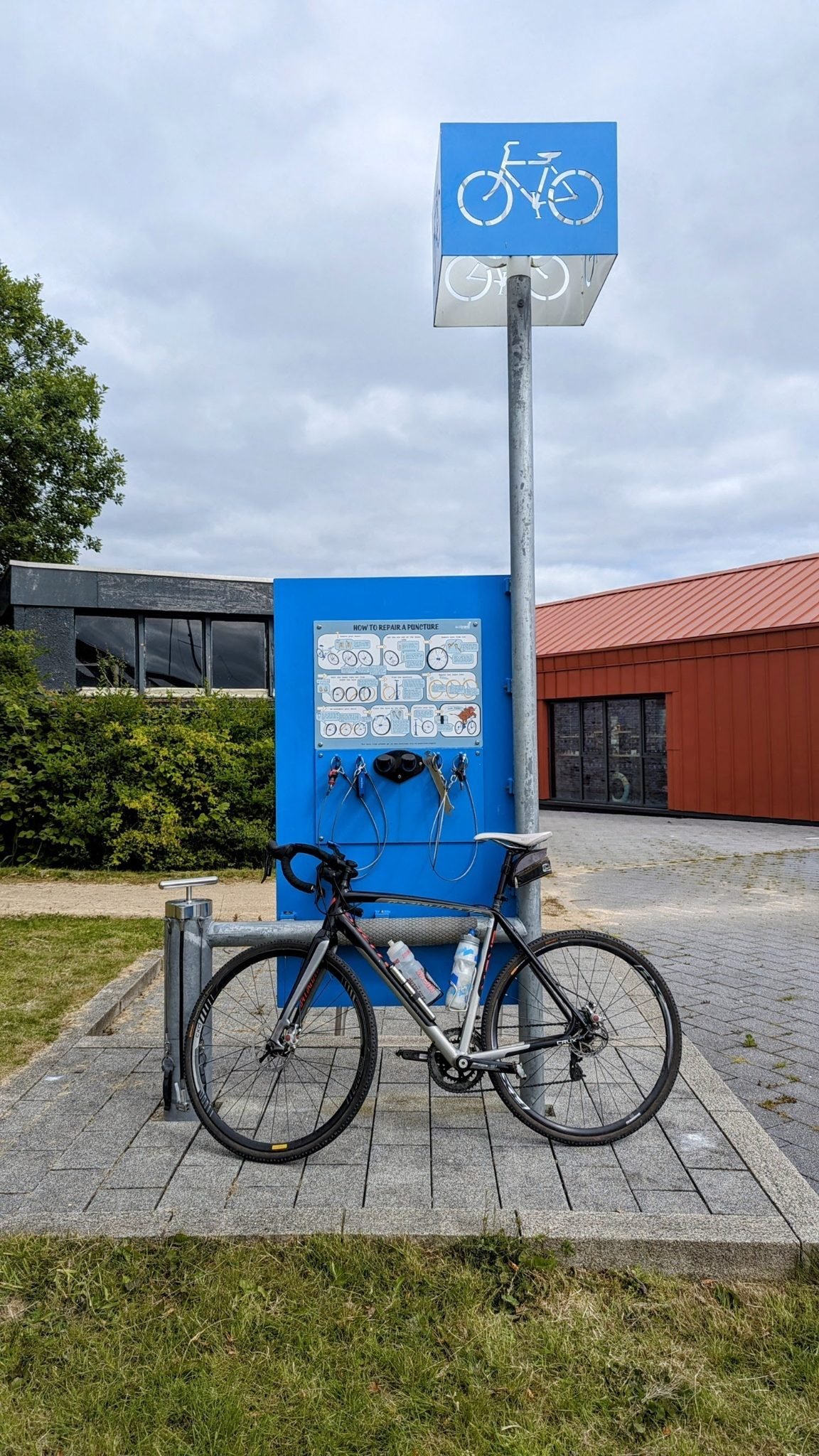 A gravel bike propped by a National Cycle Network signpost at Ardrishaig, the start of the Crinan Canal towpath.