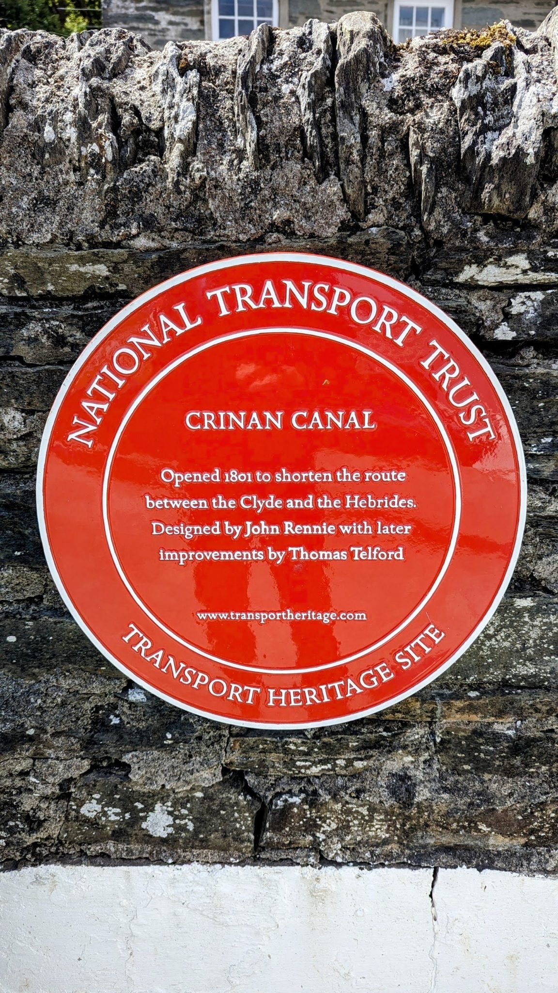 A red National Transport Trust plaque reading 'Crinan Canal, opened 1801… designed by John Rennie with later improvements by Thomas Telford.'