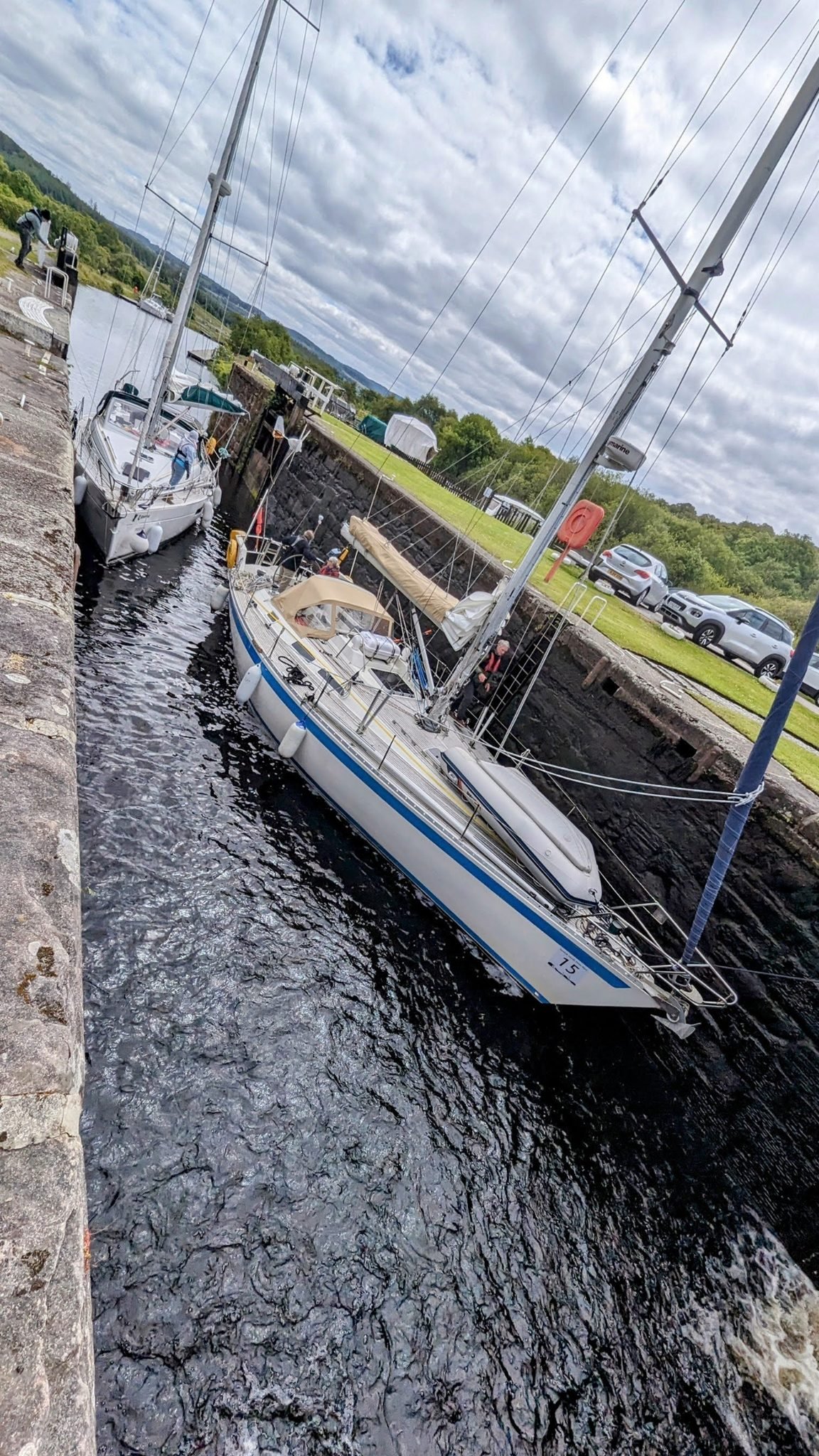 A yacht sitting low inside a stone lock chamber on the Crinan Canal, waiting for the water to rise.