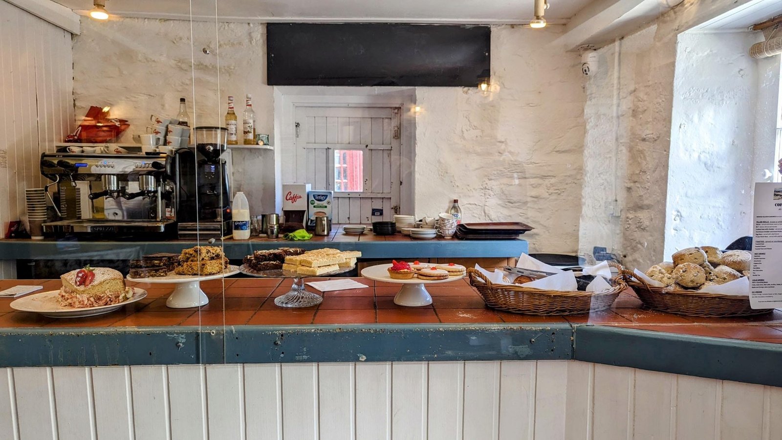 Inside the Crinan Coffee Shop, a counter laden with cakes, scones and traybakes.
