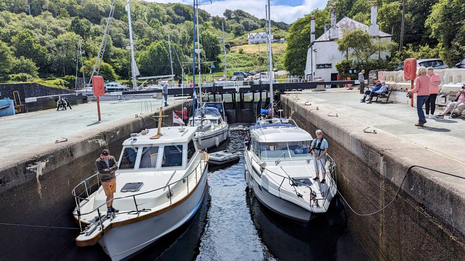 Motor cruisers and yachts moored in the sea-lock basin at Crinan, hills and sea beyond.
