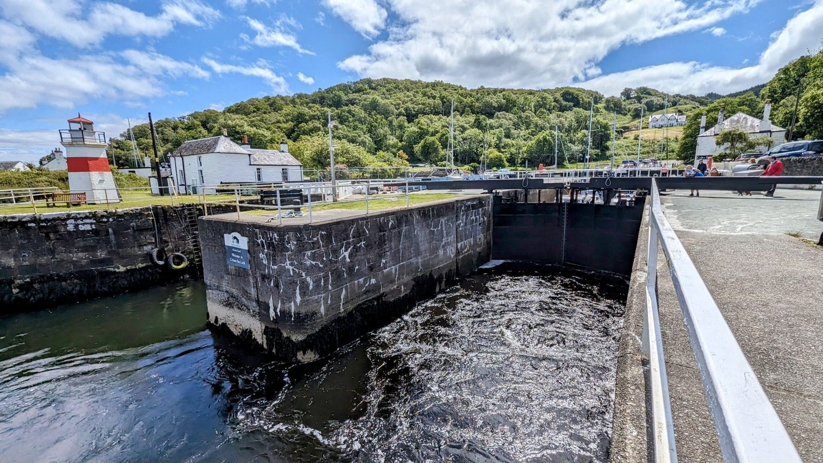 The Crinan sea lock and a small white lighthouse at the western end of the Crinan Canal.