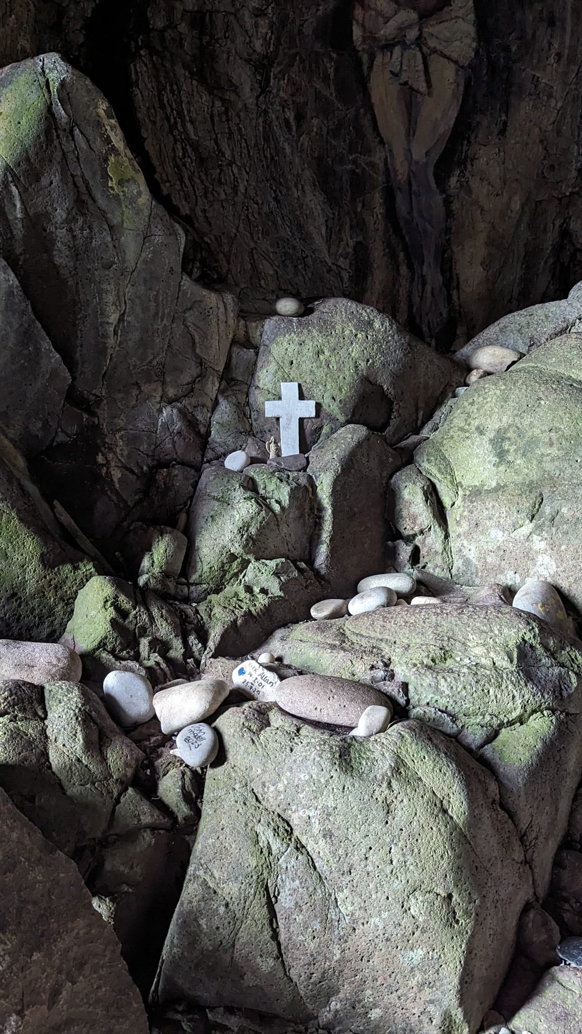 A small shrine of white stones and a white cross arranged on the rocks below the cave painting on Davaar Island.