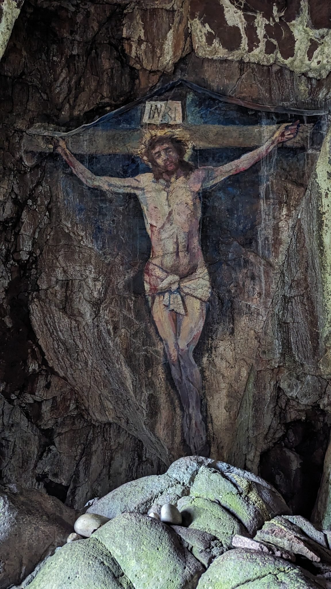 A life-size painting of the crucified Christ on the rock wall inside a sea cave on Davaar Island.