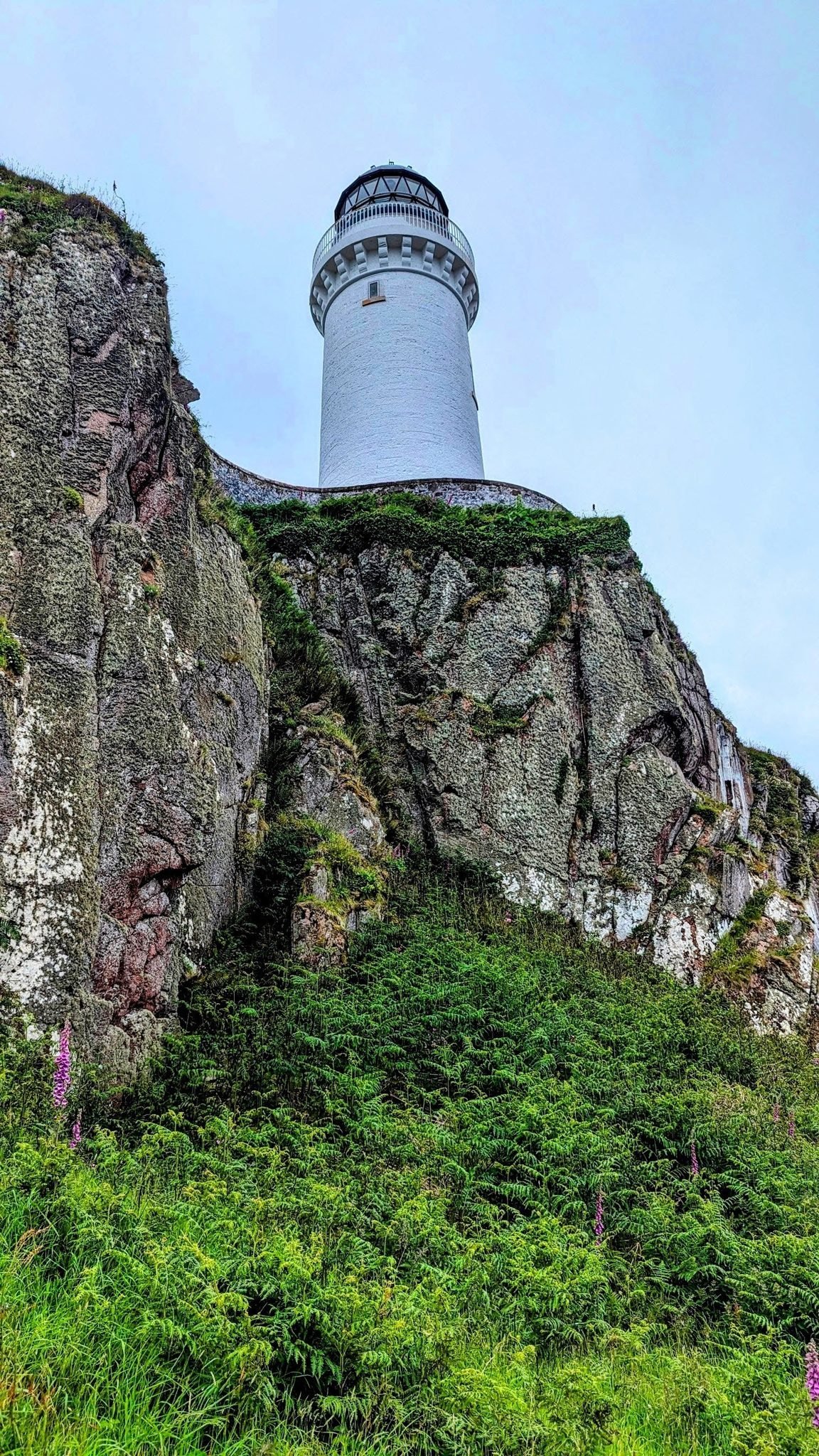The white Davaar Island lighthouse standing on a rocky clifftop above the sea at the mouth of Campbeltown Loch.