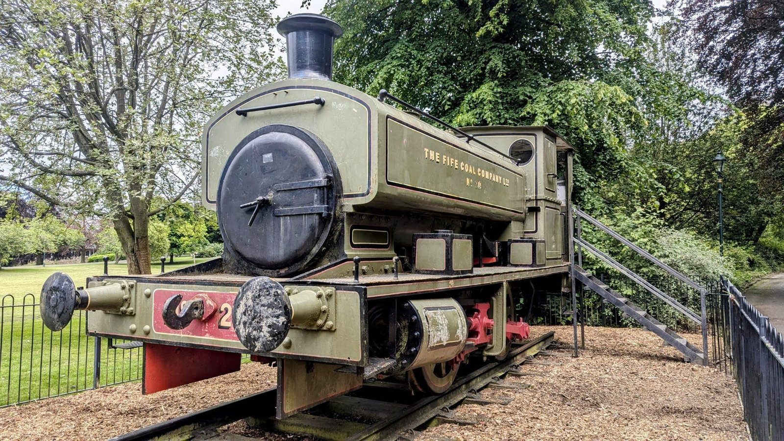 A preserved green Fife Coal Company industrial steam locomotive on display in Pittencrieff Park.