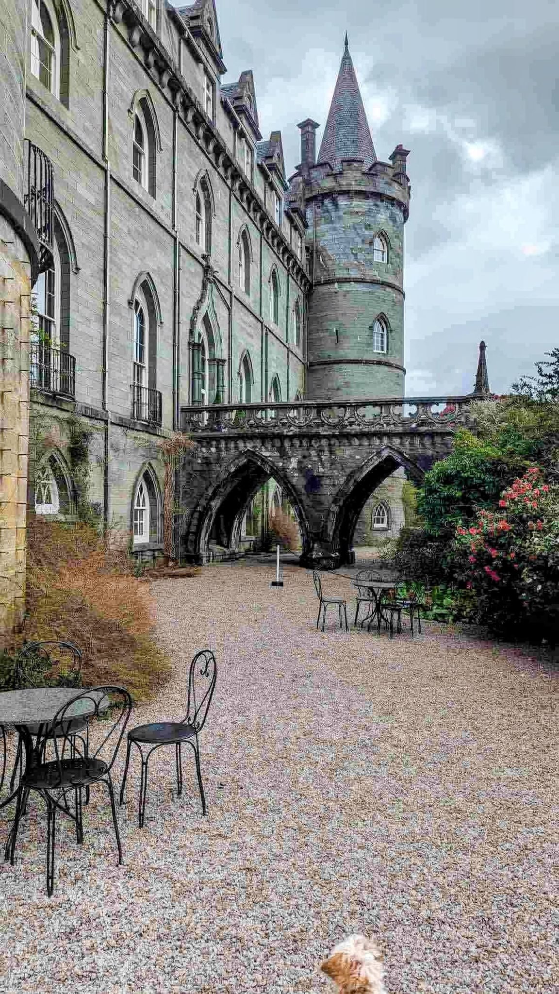The courtyard tea room at Inveraray Castle, café tables set out beside an arched stone bridge.