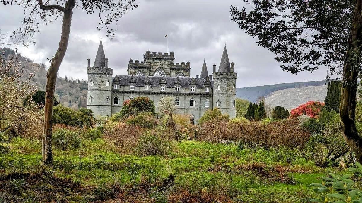 Inveraray Castle framed by trees and spring rhododendrons in its grounds.