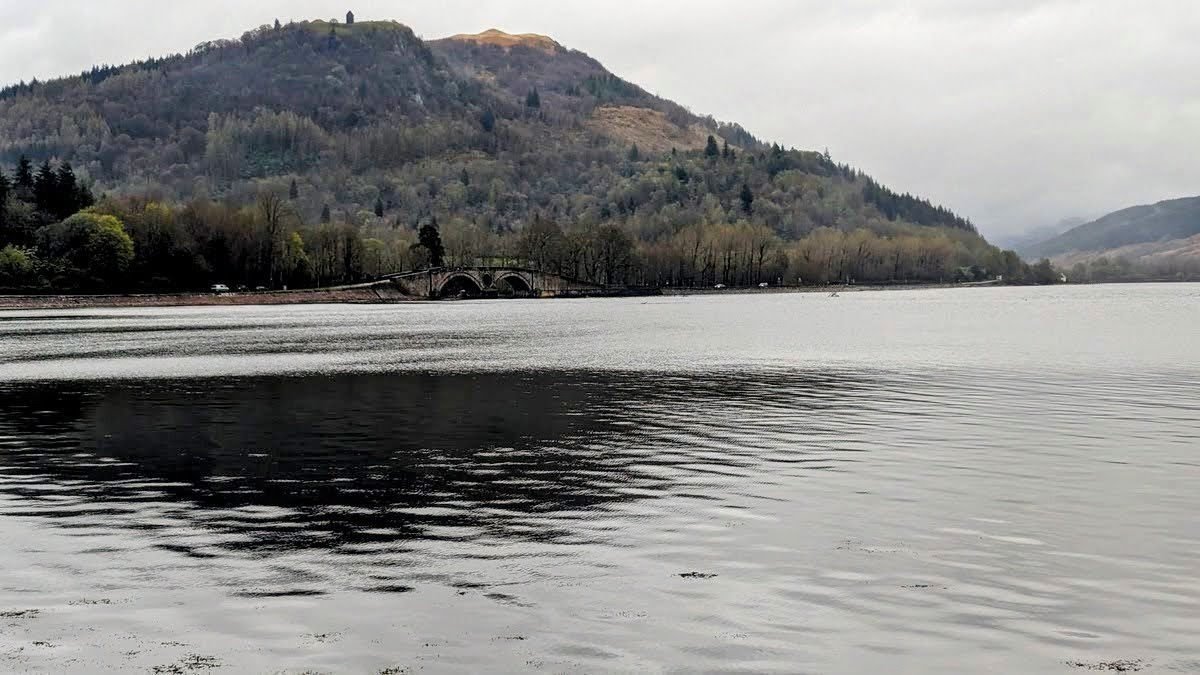 Loch Fyne and the arched bridge at Inveraray with the wooded hill of Dun na Cuaiche and its watchtower folly behind.