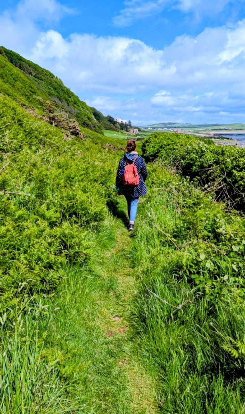 A walker on a green coastal path above the sea near Keil, southern Kintyre.
