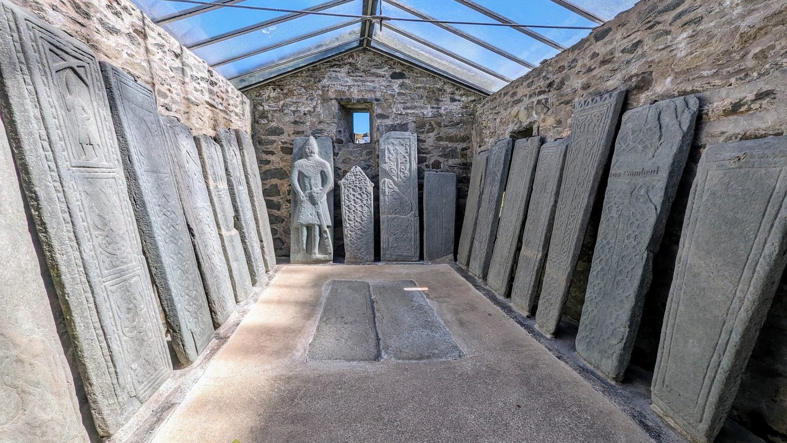 The stone-slabbed interior of the Nether Largie South chambered cairn, roofed and lit, with upright slabs forming a passage.