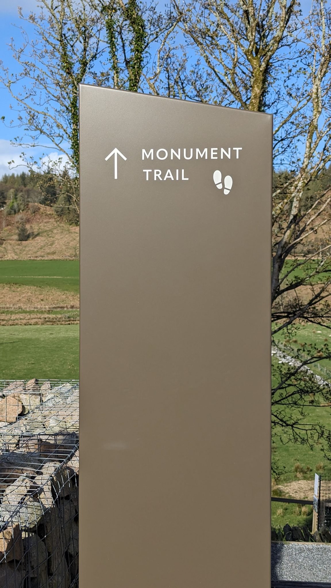 A tall metal 'Monument Trail' waymarker sign at the start of the Kilmartin Glen walk.