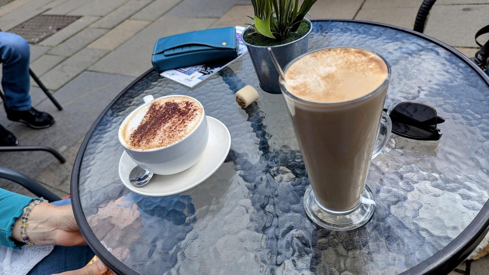 A cappuccino and a latte on an outdoor café table in Linlithgow.
