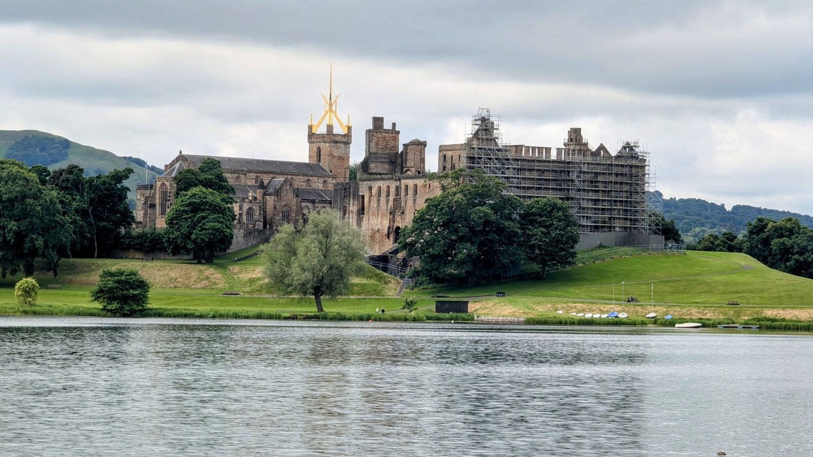 Linlithgow Palace and St Michael's spire seen across the calm water of Linlithgow Loch.