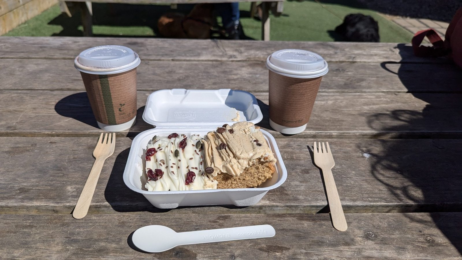 Two takeaway coffees and a tub of gelato and cake on a wooden picnic table in North Berwick.