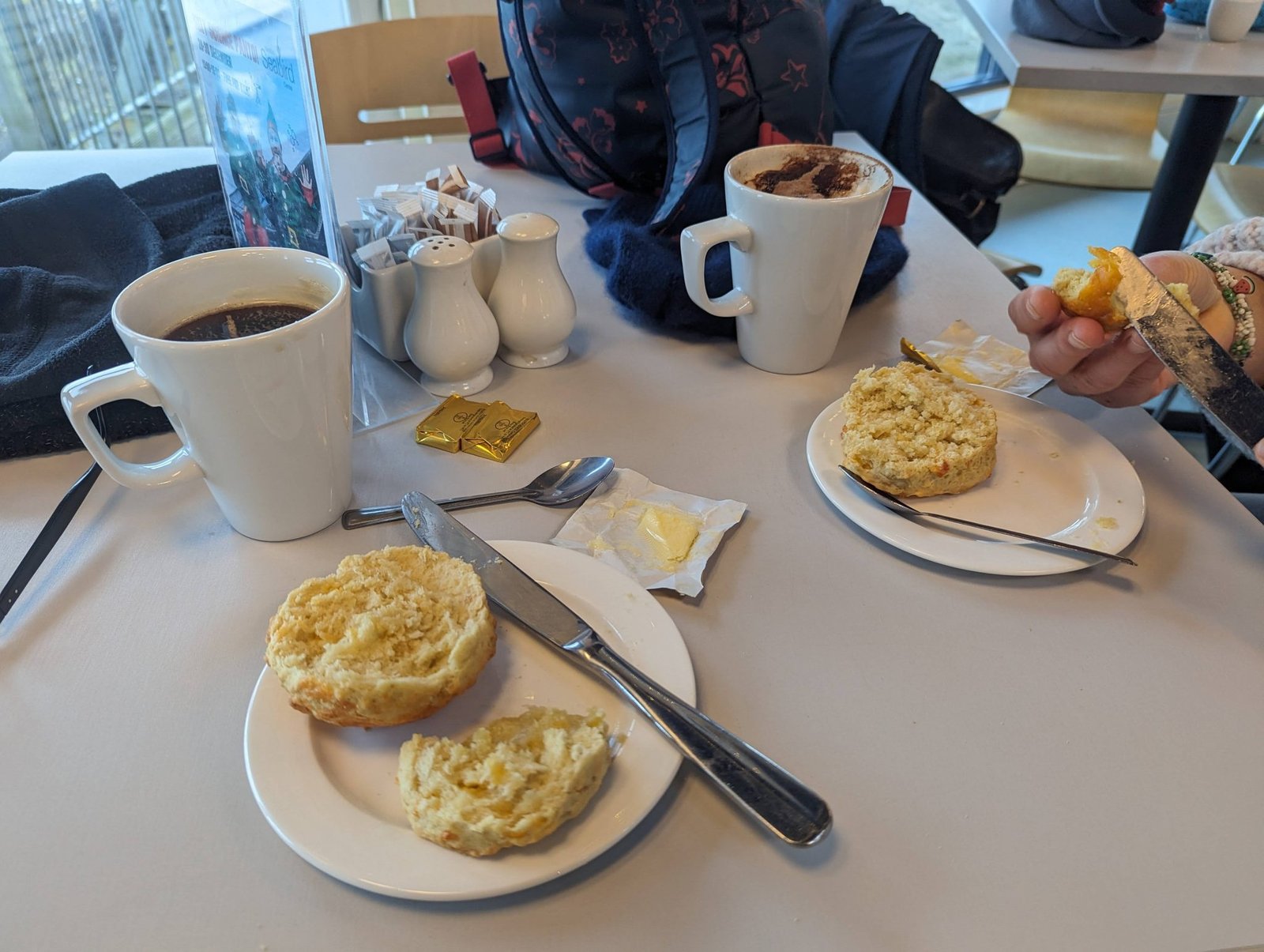 Two coffees and warm buttered scones on a café table in North Berwick.