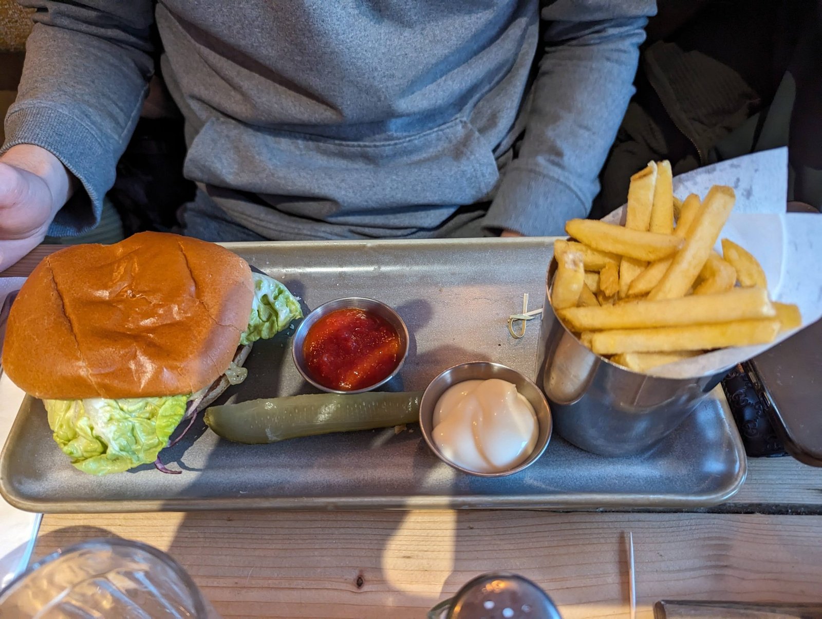 A chicken burger with fries, pickle and dips served on a metal tray at a North Berwick café.
