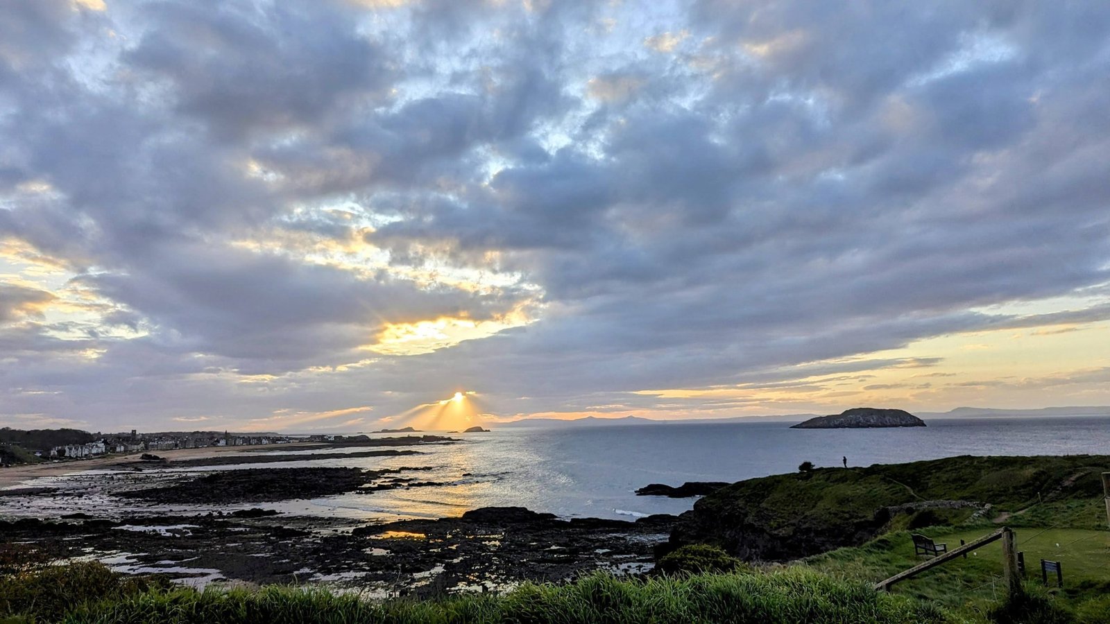 Sunbeams breaking through cloud over the Firth of Forth and its islands at North Berwick, seen from the coast at dusk.