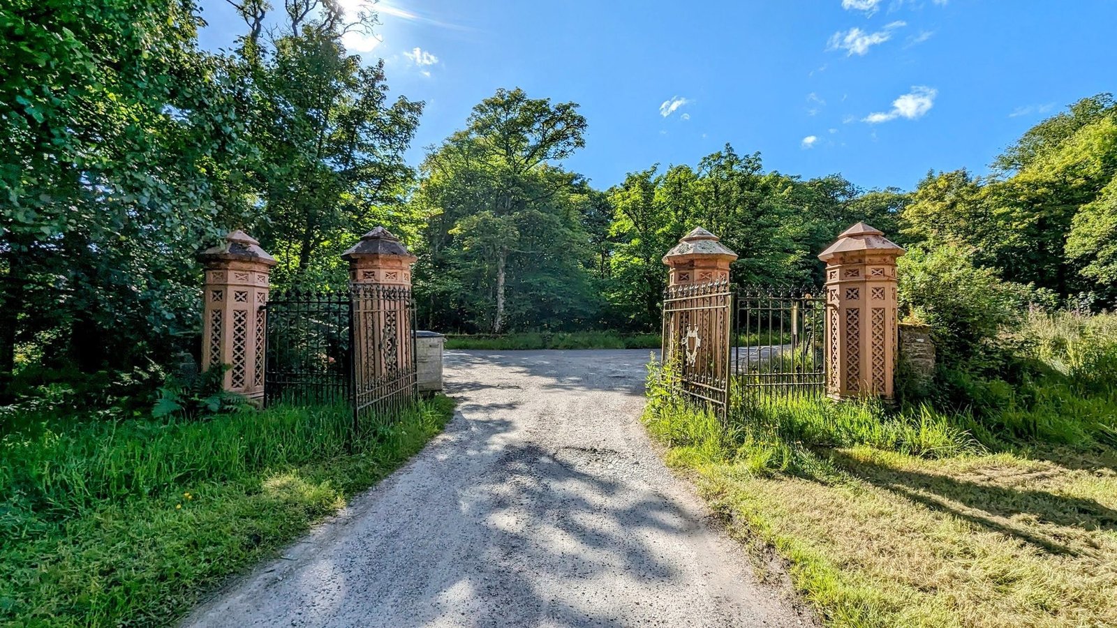 Ornate red-sandstone and wrought-iron estate gates with a heraldic panel at Skipness.