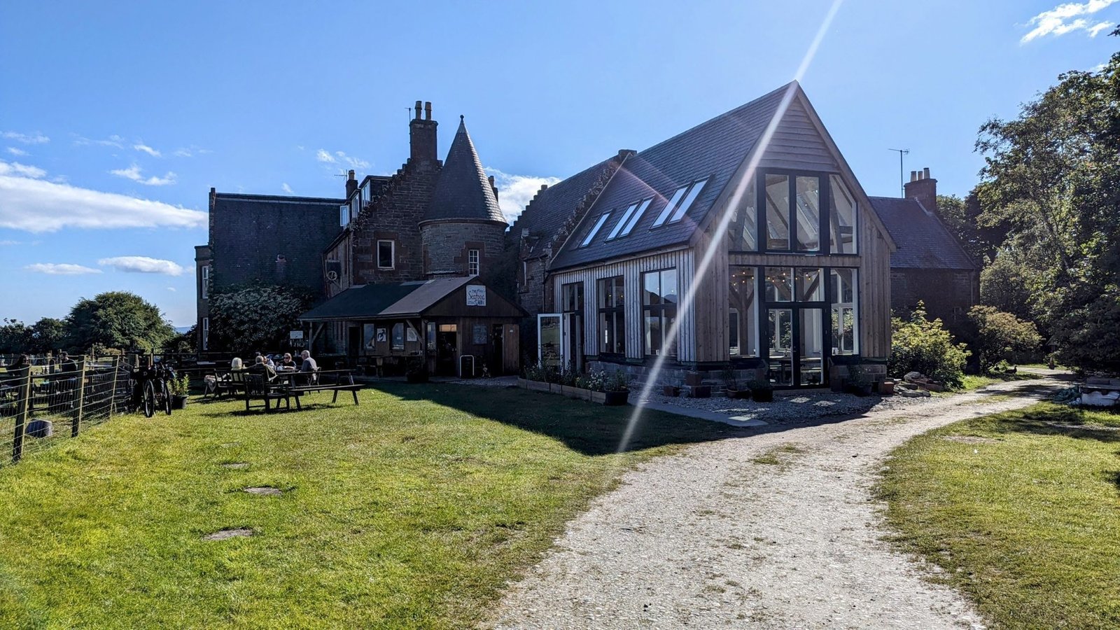 The Seafood Cabin at Skipness — a timber cabin and glass-gabled dining room beside baronial Skipness House, with picnic tables and diners outside.