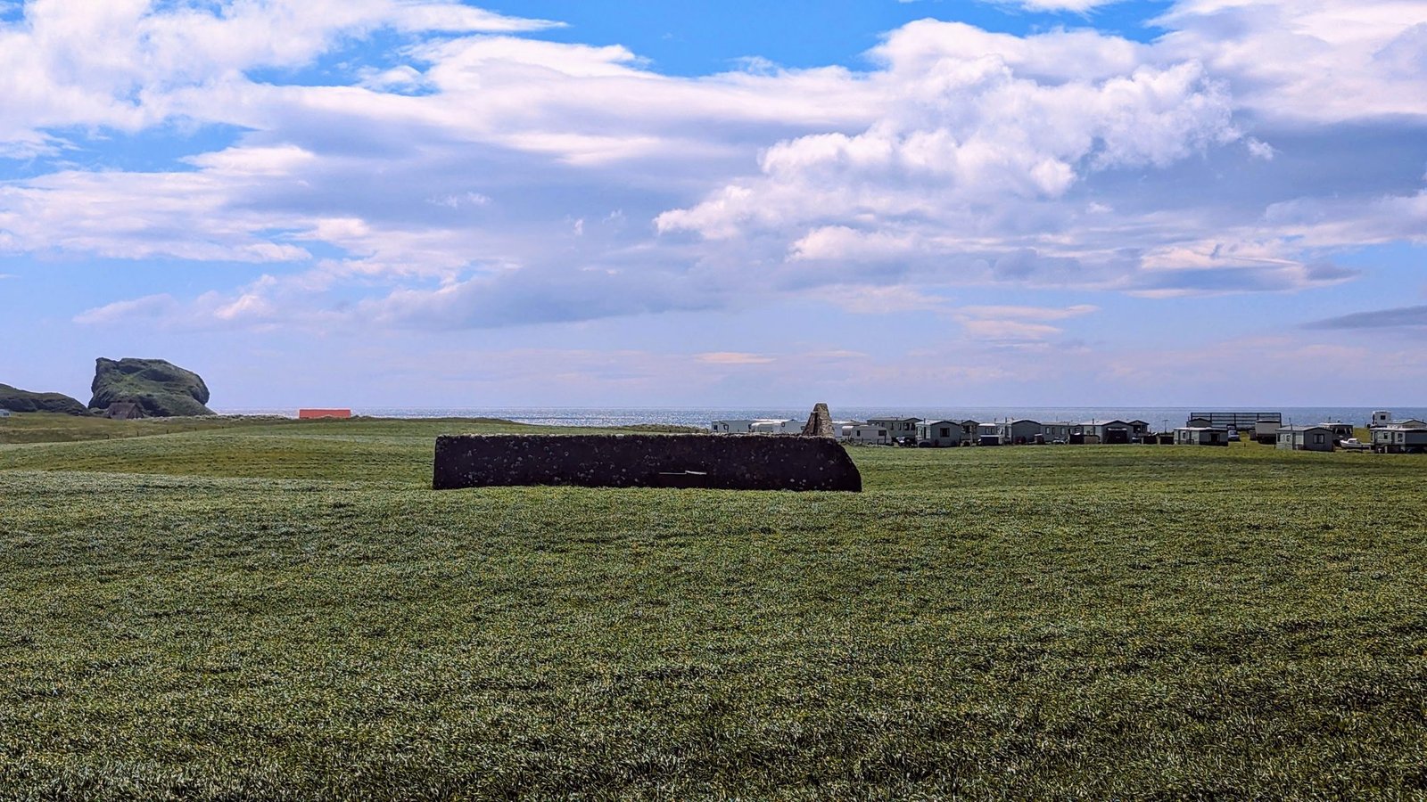 The low stone 1647 Dunaverty Massacre Memorial in a green field below Dunaverty Rock at Southend.
