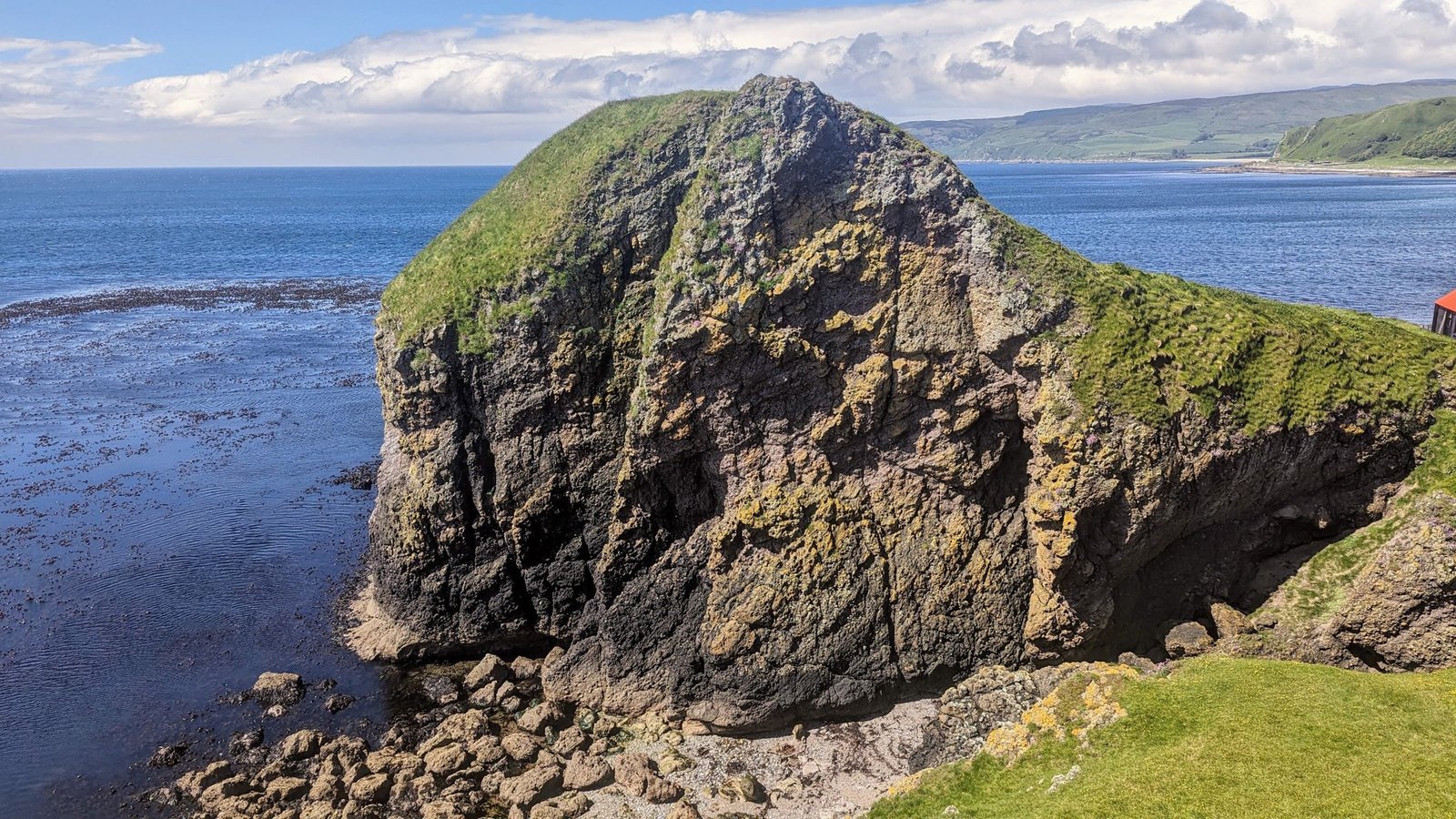 The dramatic green-topped Dunaverty Rock rising from the sea at Southend, Kintyre, once the site of Dunaverty Castle.